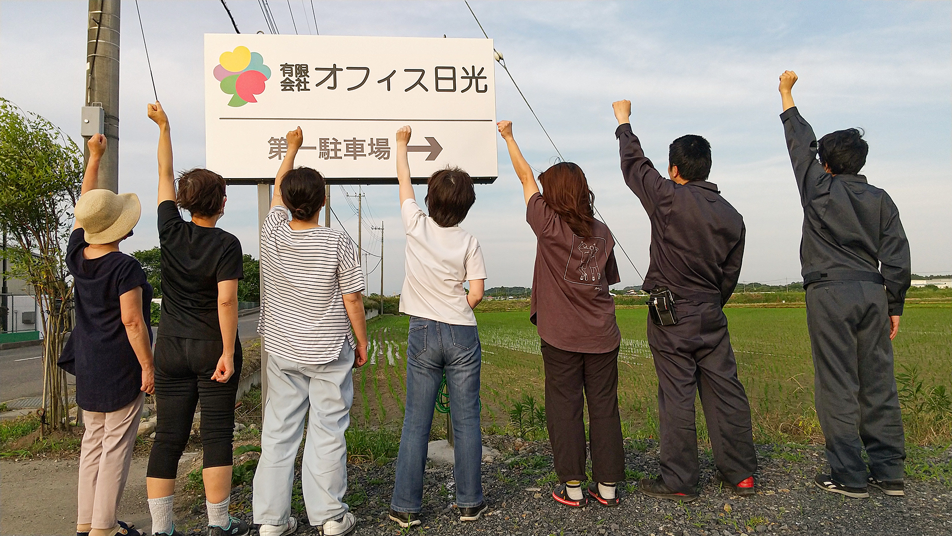 新しい看板の前で仲間のポーズ！の写真