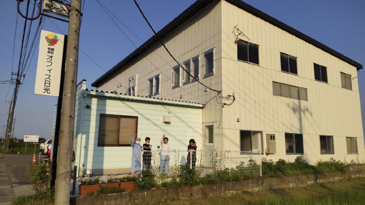 社員入口でポーズする社員の写真